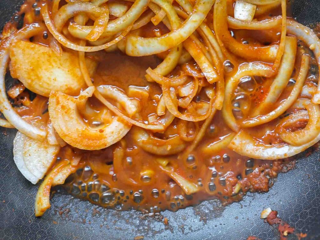 onions cooking in broth and curry paste